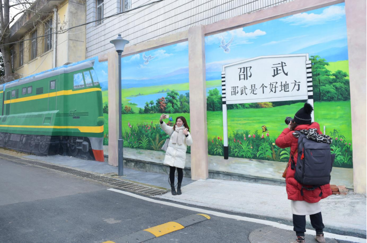 游客在邵武市水北街道太保路文化墙打卡点观赏、阅览